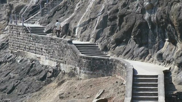 Man walking up the stairs outside of Aurangabad caves.