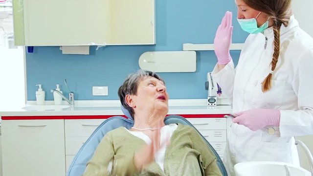 Elderly friendly woman doing high five with dentist after receiving injection
