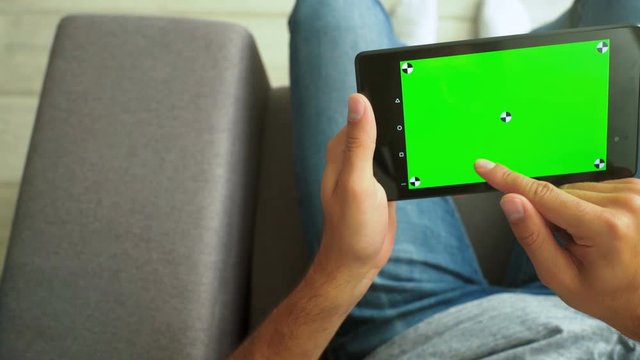 Handsome man using tablet pc at home green screen, chroma key, tracking points