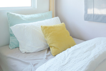 Yellow and green pillow on tiny bed in kid bedroom interior