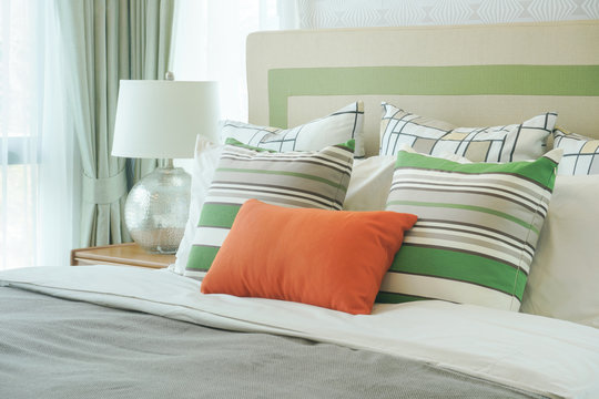 Orange pillow with green pattern pillows on bed