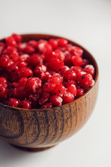 Frozen redcurrant with frost in wooden bowl
