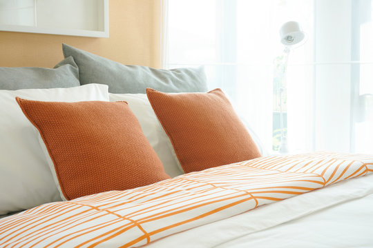 Lively style bedding, orange pillows setting on bed