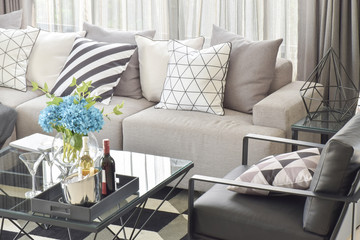Mix pattern pillows in gray tone sofa and wine bottles on center table in living room