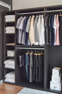modern closet with row of cloths hanging in black wardrobe
