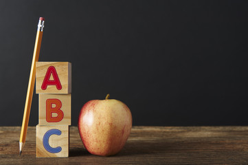 ABC Wooden spelling blocks, pencil and apple on wooden table