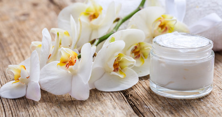 Obraz na płótnie Canvas Moisturizing cream and orchid on wooden background