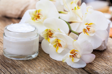 Fototapeta na wymiar Moisturizing cream and orchid on wooden background