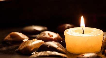 Candle and pebbles in water background