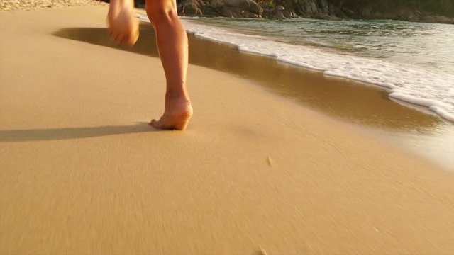 Feet little girls run barefoot on the golden sand beach. Slow motion.