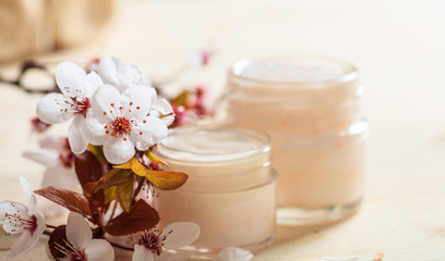 Moisturizing cream and cherry blooms on wooden background