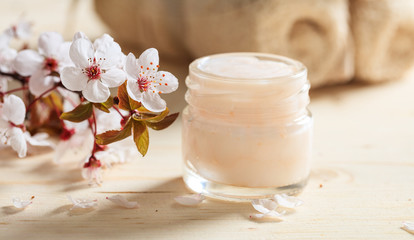 Fototapeta na wymiar Moisturizing cream and cherry blooms on wooden background