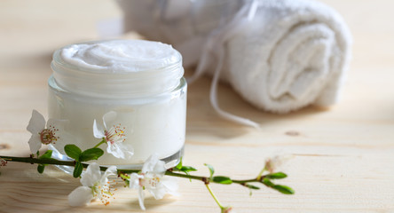 Fototapeta na wymiar Moisturizing cream and almond blooms on wooden background