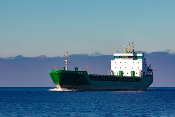 Green cargo ship moving in still water of Baltic sea