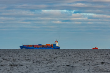 Blue container ship sailing in still Baltic sea water