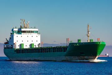 Green cargo ship moving in still water of Baltic sea