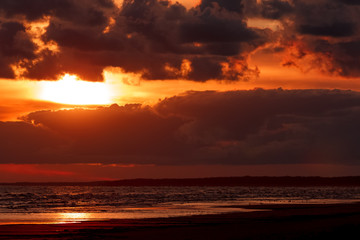 Naklejka na ściany i meble Orange cloudy sunset sky over the Baltic sea