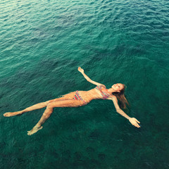 Woman in bikini relaxing lying on the water