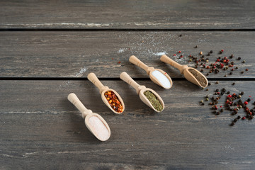 Various of spices and in wooden spoons. Flat lay of spices ingredients chilli, salt, himalayan salt, savory and black pepper on grey wooden board.