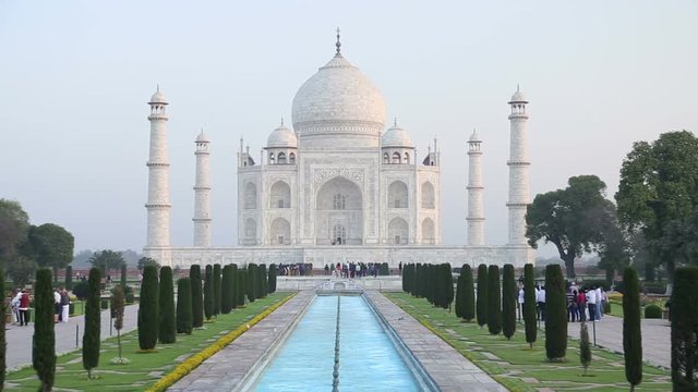 Taj Mahal front view, with tourists walking in garden.