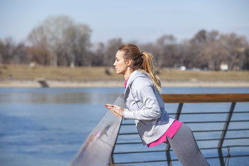 Young woman on recreation and jogging.Warm up and stretch muscles before exercise by the river