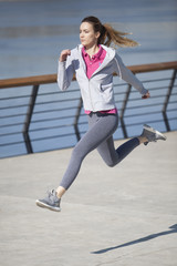 Morning exercise near the river. Young woman on recreation and jogging.