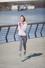 Obraz premium Morning exercise near the river. Young woman on recreation and jogging.