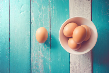eggs in a white bowl on the ocean blue table view from above.