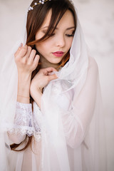 Bride's morning. Fine art wedding. Portrait of a young bride in white lace boudoir with wavy blonde...