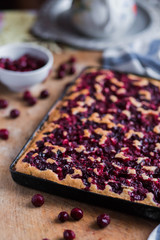 cherry fruit pie on a black baking tray on wooden Board with white blue kitchen towels close-up