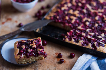 a piece of cake saucers cherry fruit pie on a black baking tray on wooden Board with white blue kitchen towels close-up