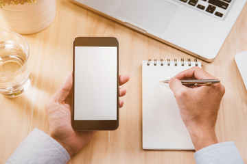 Businessman hand holding a phone with isolated screen over the desk in the office