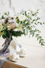 beautiful white Bridal shoes and a beautiful bouquet on the piano near the window on a white background