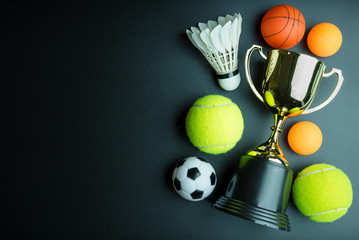 Golden trophy, Football toy, Baseball toy, Ping pong ball, Shuttlecock and Tennis isolated on black background with copy space.Concept winner of the sport.