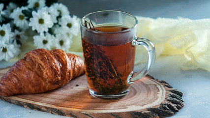 Breakfast cup of tea with thyme and croissant