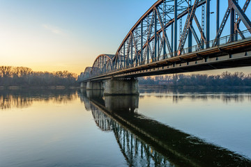 Naklejka na ściany i meble Jozef Pilsudski road bridge reflected in Vistula river in the morning. Torun, Poland. Europe.