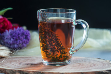 Cup of tea with thyme and bouquet of flowers on background. Spring concept