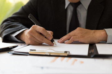 Businessman analyzing charts and graphs and taking notes.
