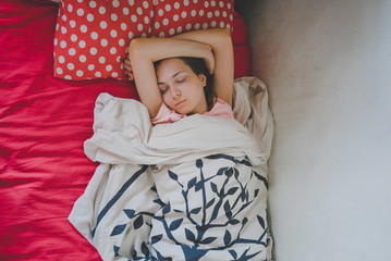 Девушка спит в кровати глубоким сном с ярким пастельным бельем - obrazy, fototapety, plakaty