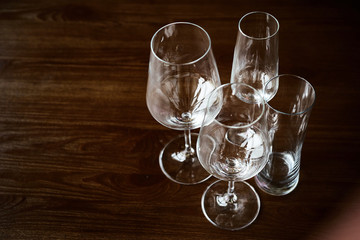 Empty clean glasses for champagne, cocktails, wine and water stand on a textured wooden table in the interior of the restaurant