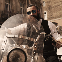Fototapeta na wymiar Serious Bearded Biker Man Sitting on a Motorcycle
