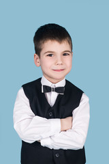 portrait of smiling little business boy with crossed arms, isolated on blue background, business suit wearing