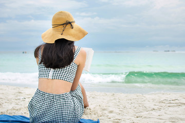 Girl reading a book on a sandy beach