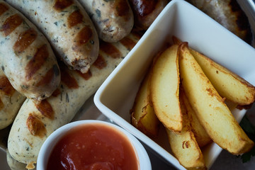 set of appetizers: grilled sausages grilled with slices of baked potato with stewed sauerkraut and grainy mustard and ketchup