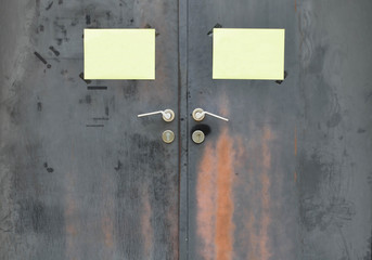 Black rusty iron door with handle and yellow paper attached