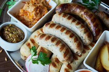 set of appetizers: grilled sausages grilled with slices of baked potato with stewed sauerkraut and grainy mustard