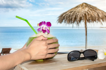 Girl holding fresh coconut at the beach resort