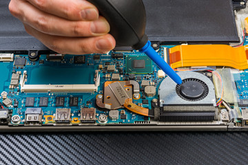 person hands cleaning laptop motherboard with a pump