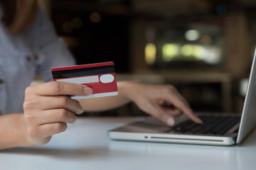 woman holding credit card with laptop computer for online shopping