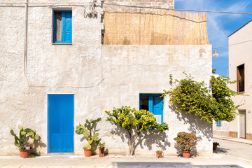 The wall with blue door and windows of the typical house in San Vito Lo Capo. 
